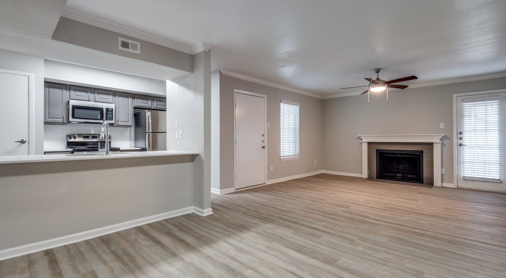 an empty living room with hardwood floors and a ceiling fan at The  Sutton