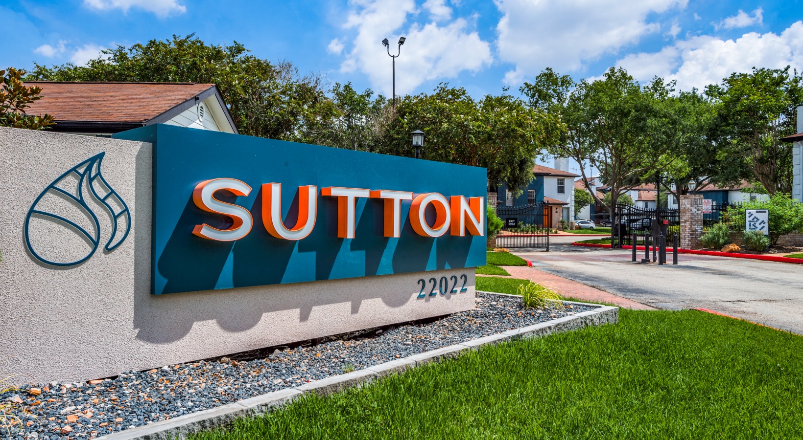 the sign for supton apartments in front of a green grassy area at The  Sutton