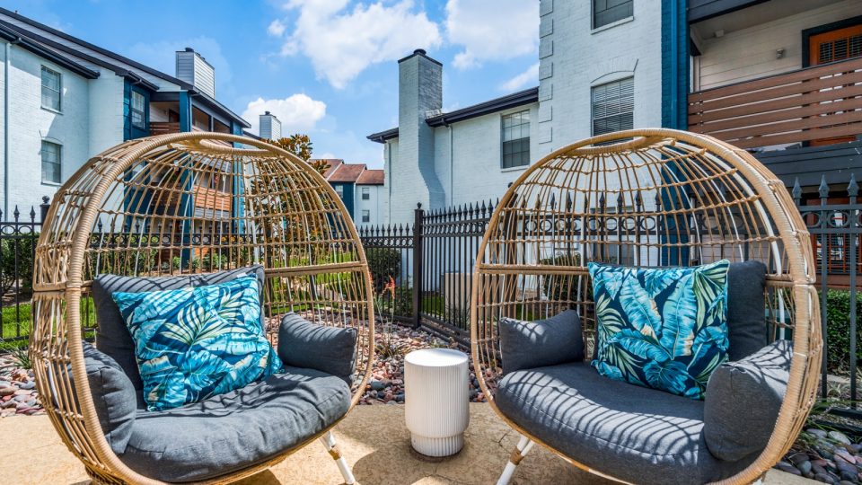 two wicker chairs sitting on a patio with a blue and white pillow at The  Sutton