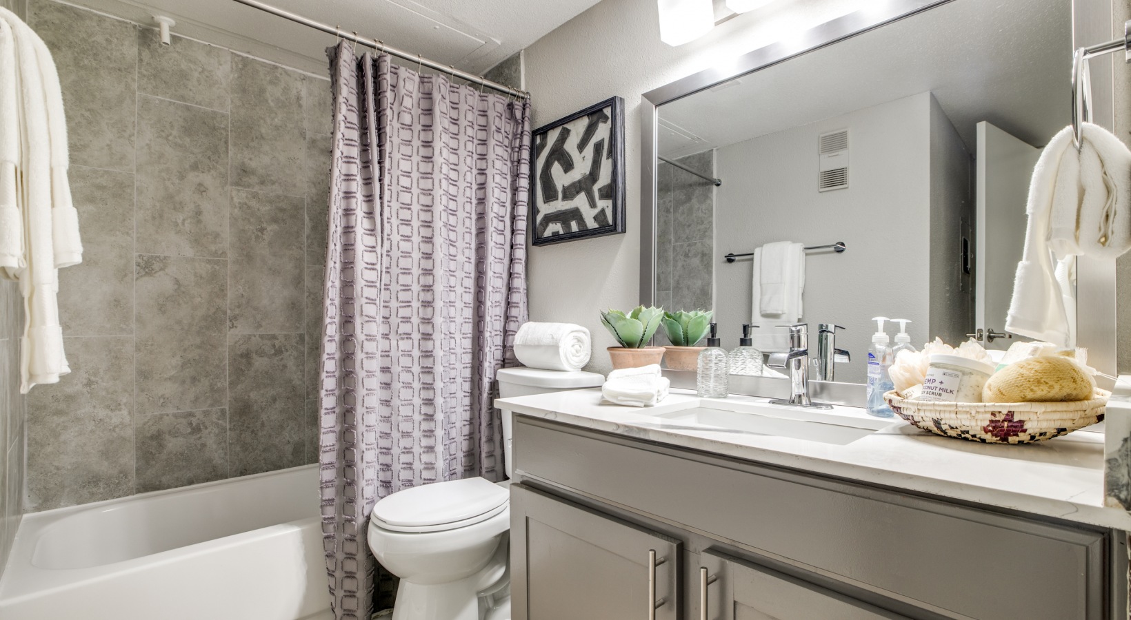 a bathroom with a shower curtain, toilet, sink and tub at The  Sutton